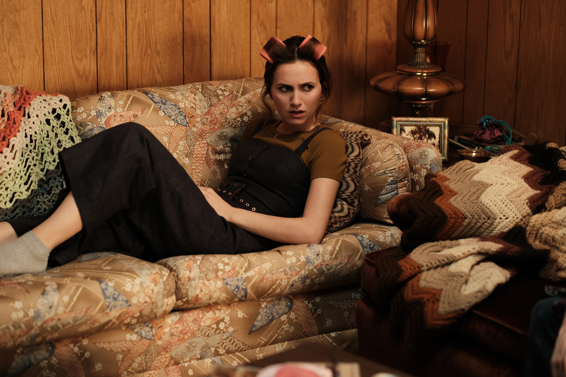 Teen girl lying on couch with curlers in her hair