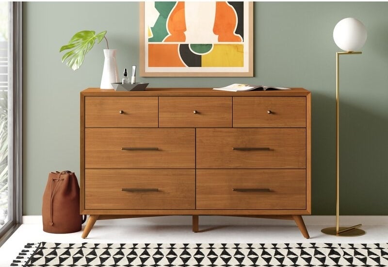 Dresser with a piece of art above it, styled with accessories and a floor lamp next to it