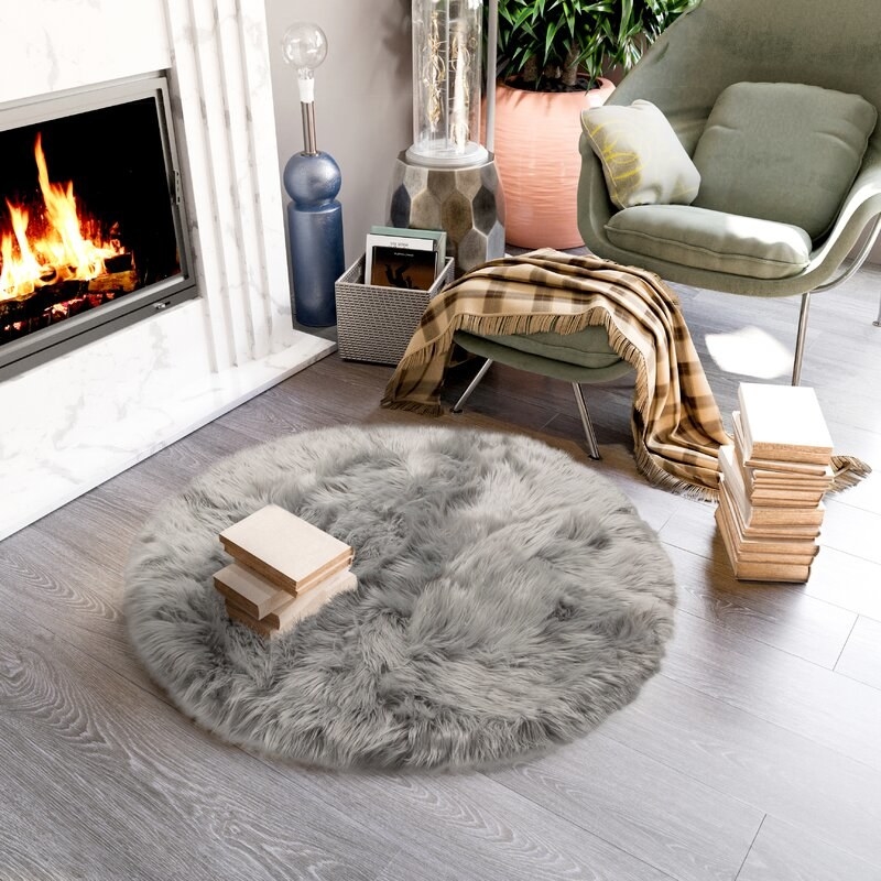 Gray rug  next to an armchair and ottoman by a fireplace