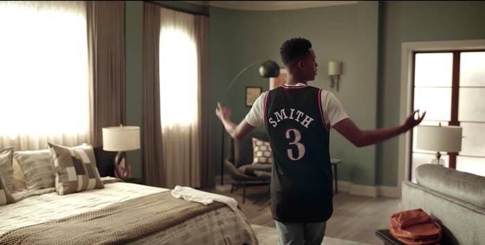 Will standing in a bedroom wearing a t-shirt and a basketball jersey that says Smith on the back