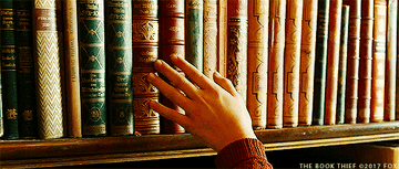 Person running their fingers along a shelf of books