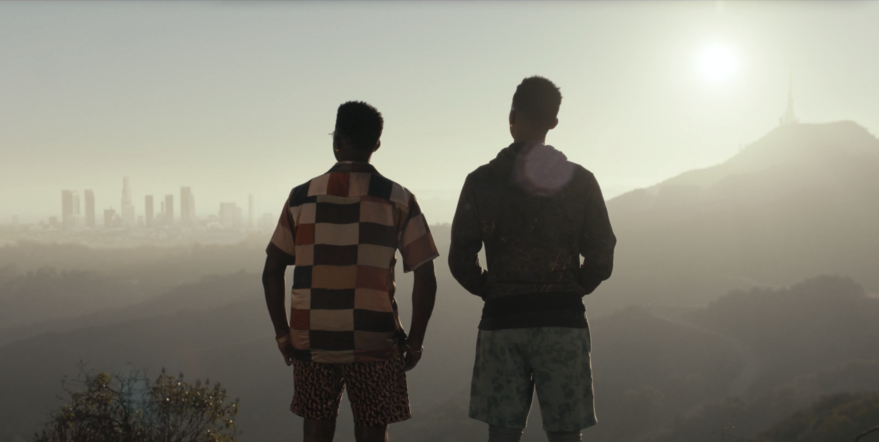 Will and Jordan L. Jones as Jazz stand with their backs to the camera looking out at the view of L.A., with buildings and hills visible in the distance
