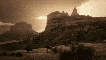 Two cowboys riding across western USA during a cloudy sunset in the game