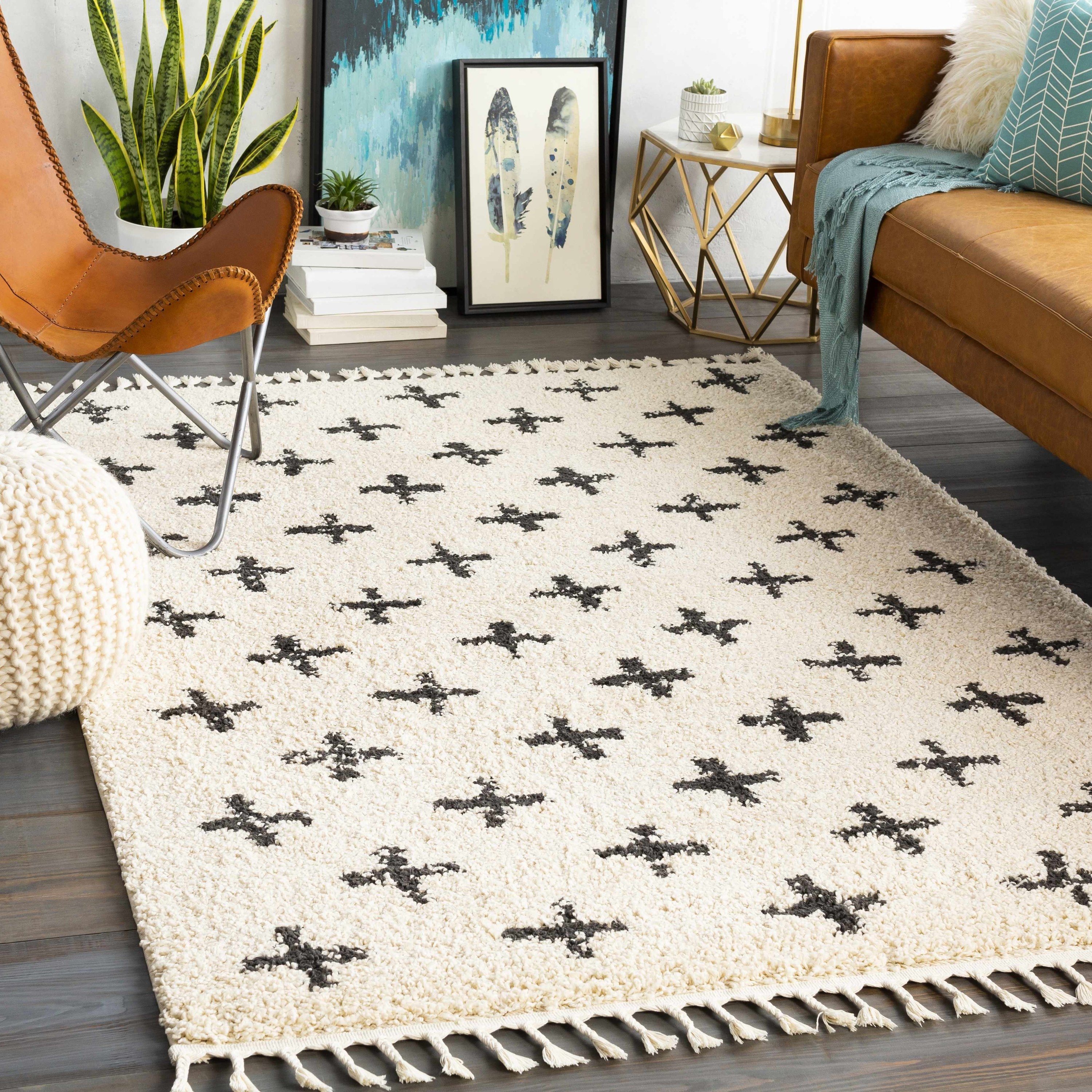an off white rug with black cross designs through it and fringed edges