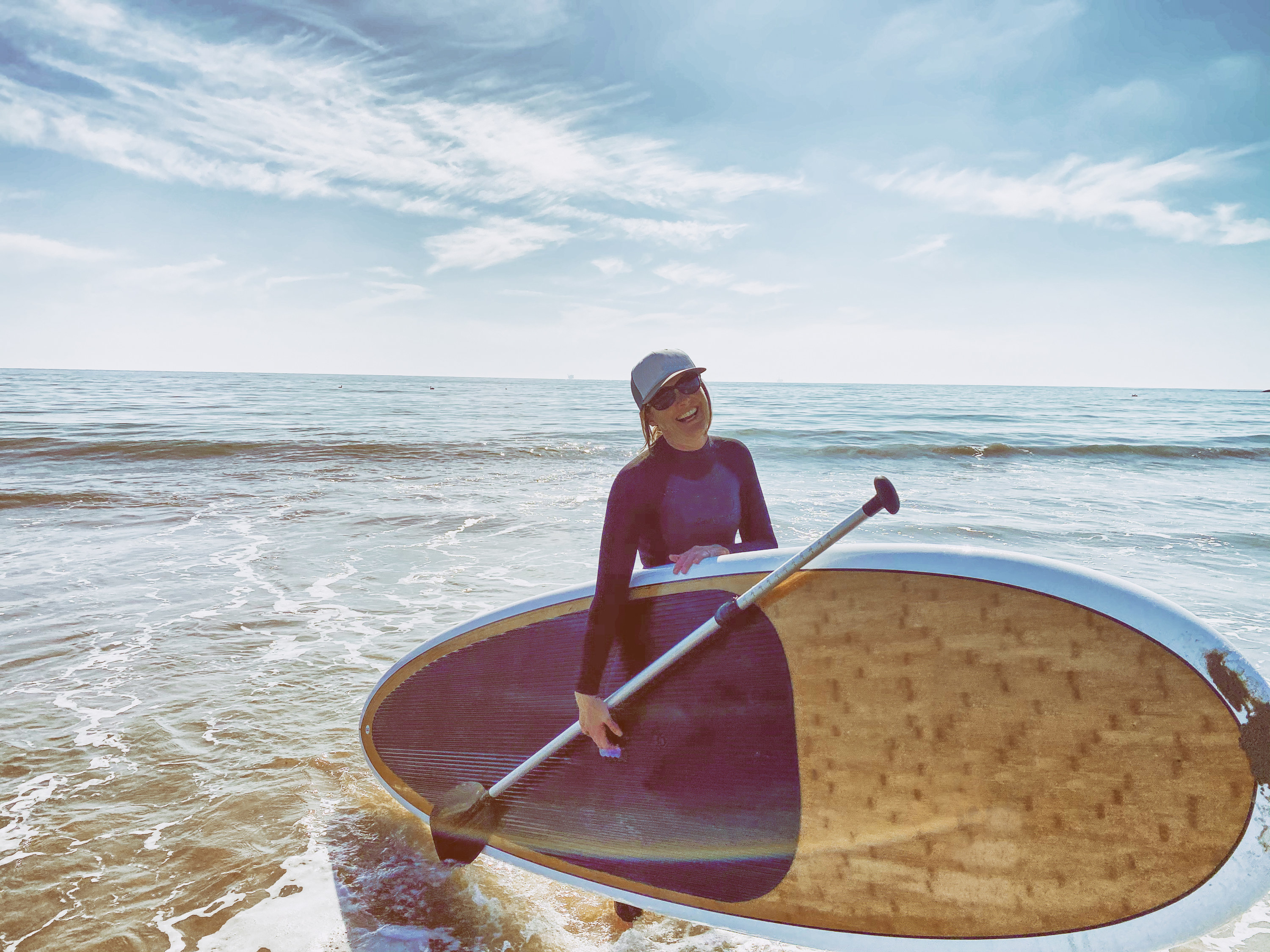 woman smiling while paddle boarding at the beach in California