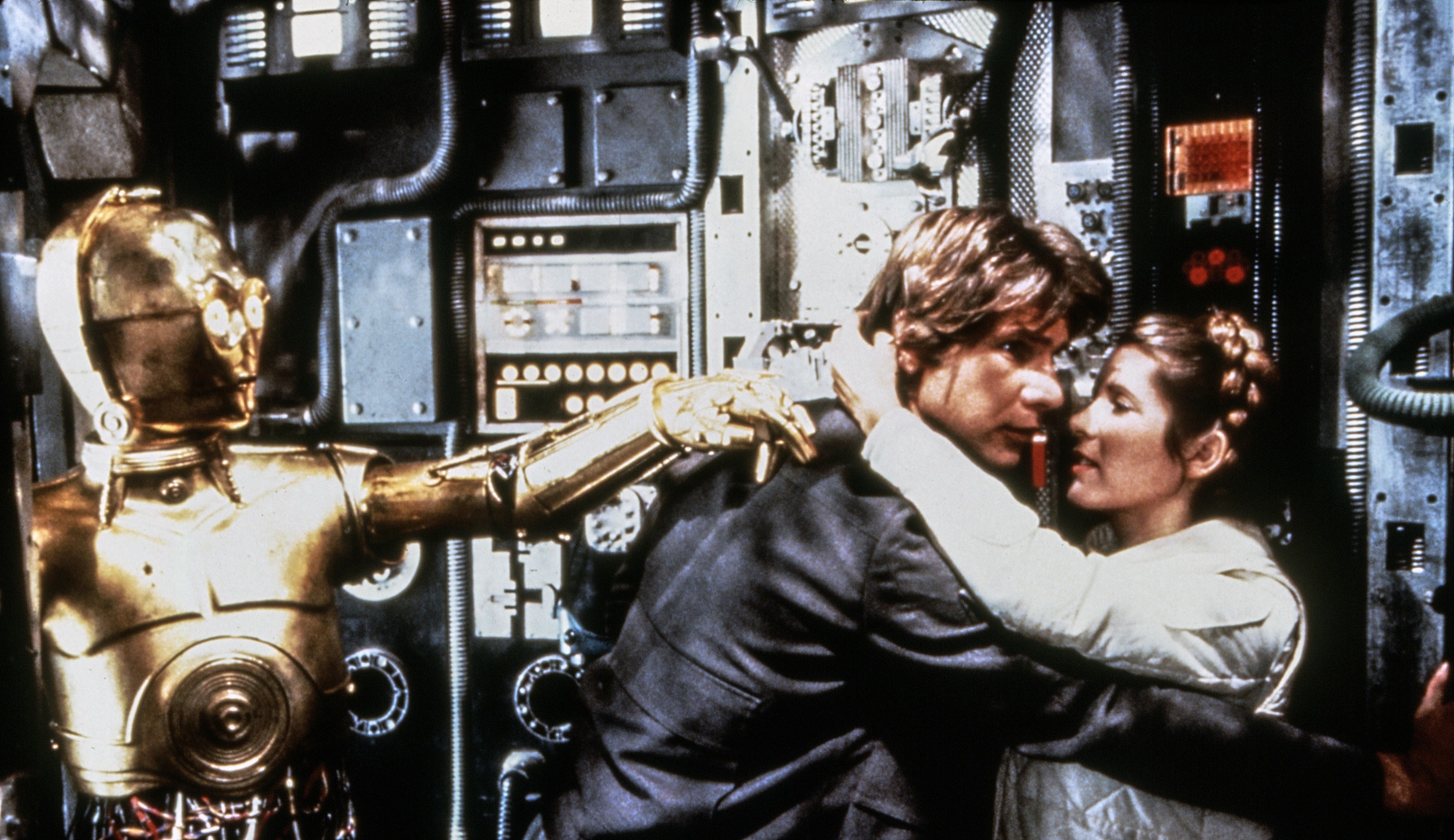 Leia and Han embrace, while C-3PO looks on
