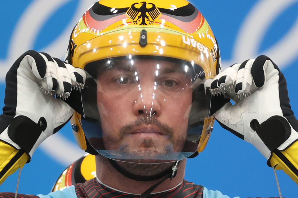 A closeup of an athlete adjusting their helmet with their gloves which are spiked on the fingertips