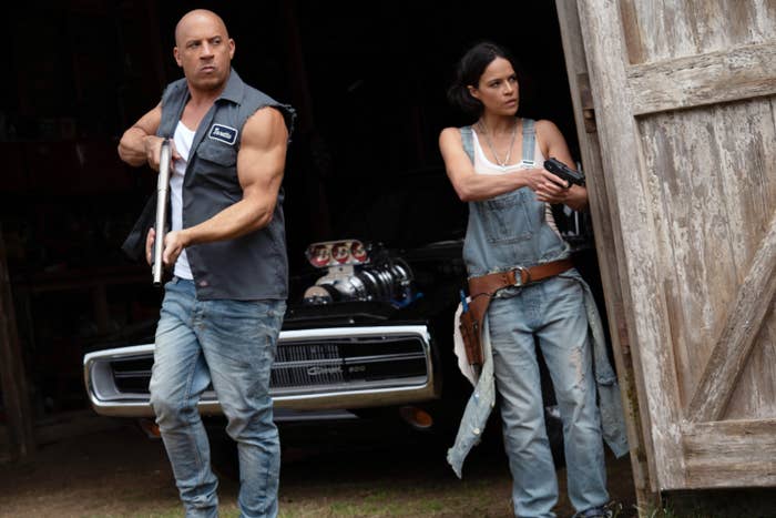 Michelle Rodriguez and Vin Diesel holding guns in a garage