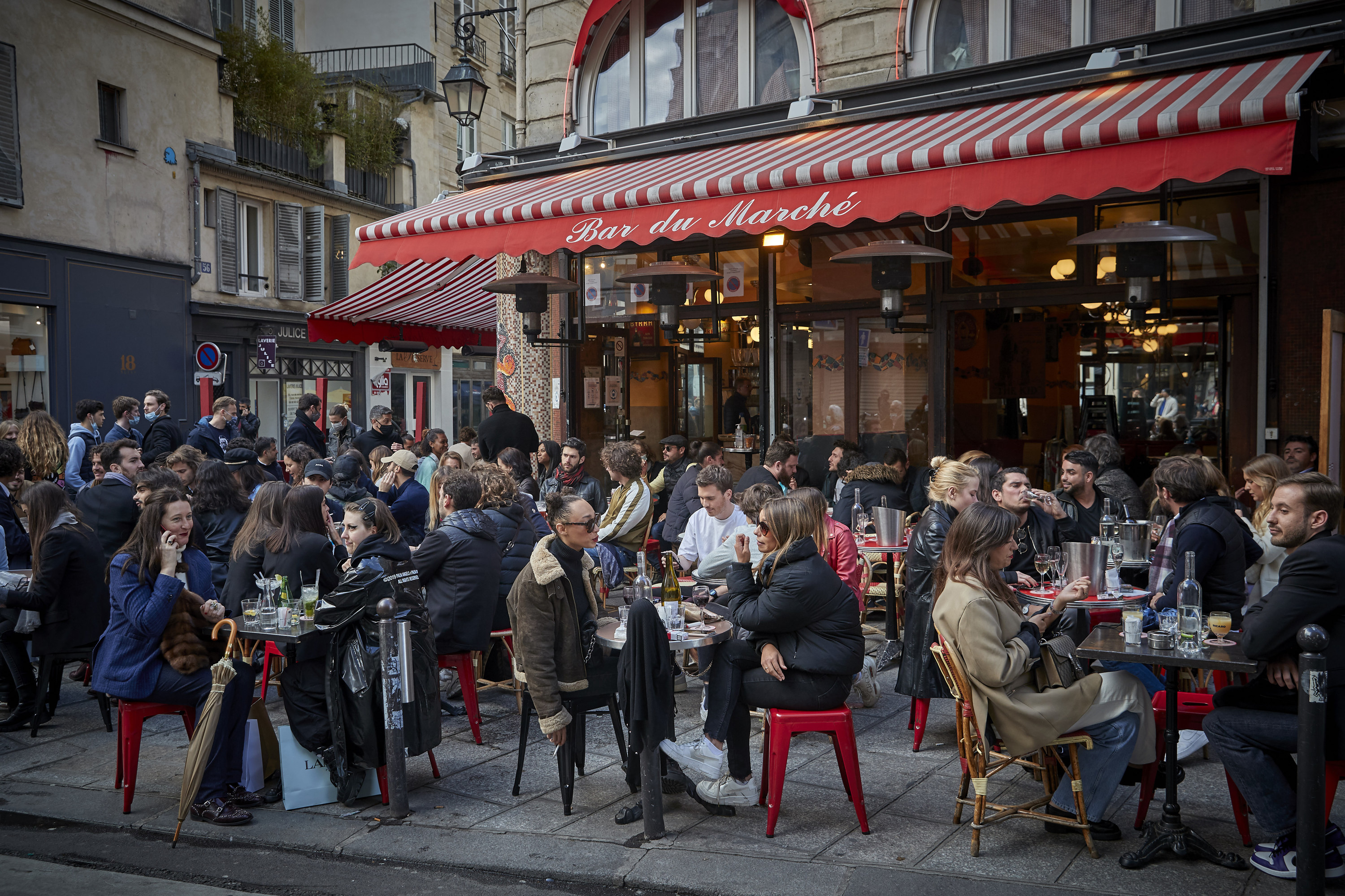 Many people eating at a sidewalk cafe in a quaint street in Paris