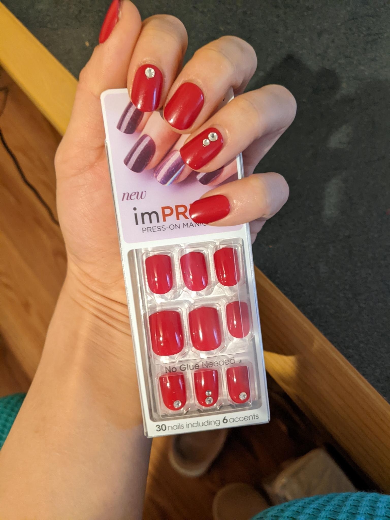 Someone wearing the press-on nails and holding the packaging