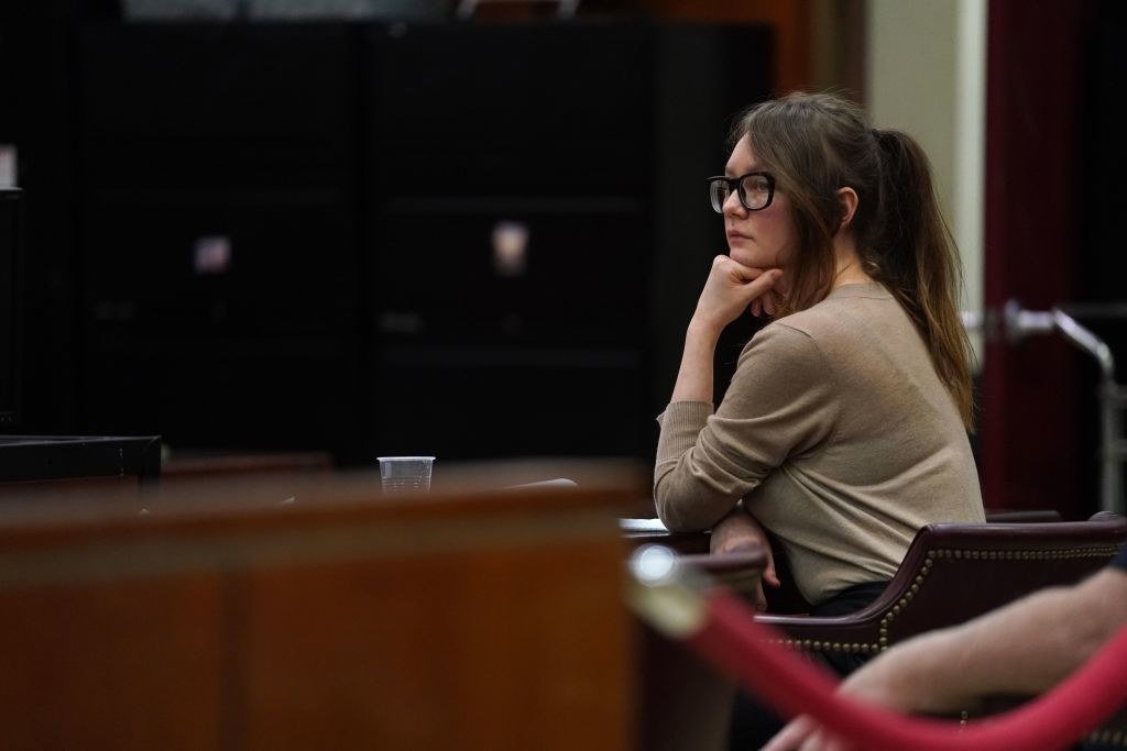 dressed in a simple sweater with her hair pulled back, the real Anna listens in her court hearing