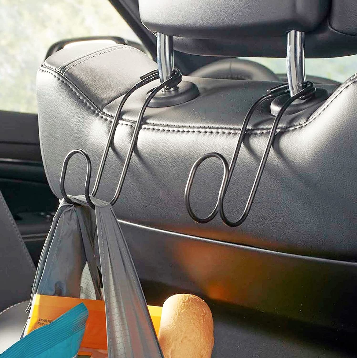 Two hooks on a headrest, on has a bag on it