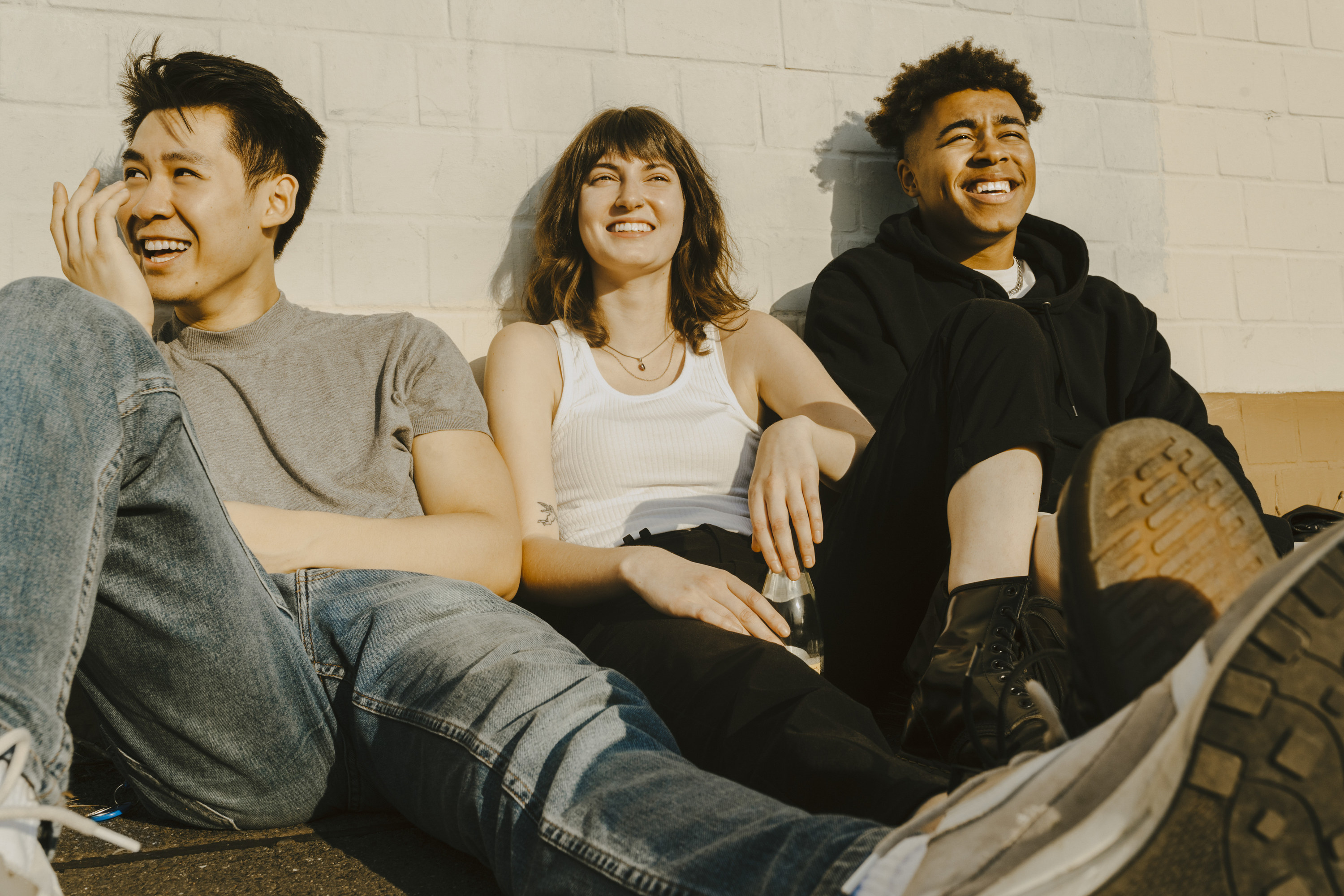 Three teens sitting together on the ground