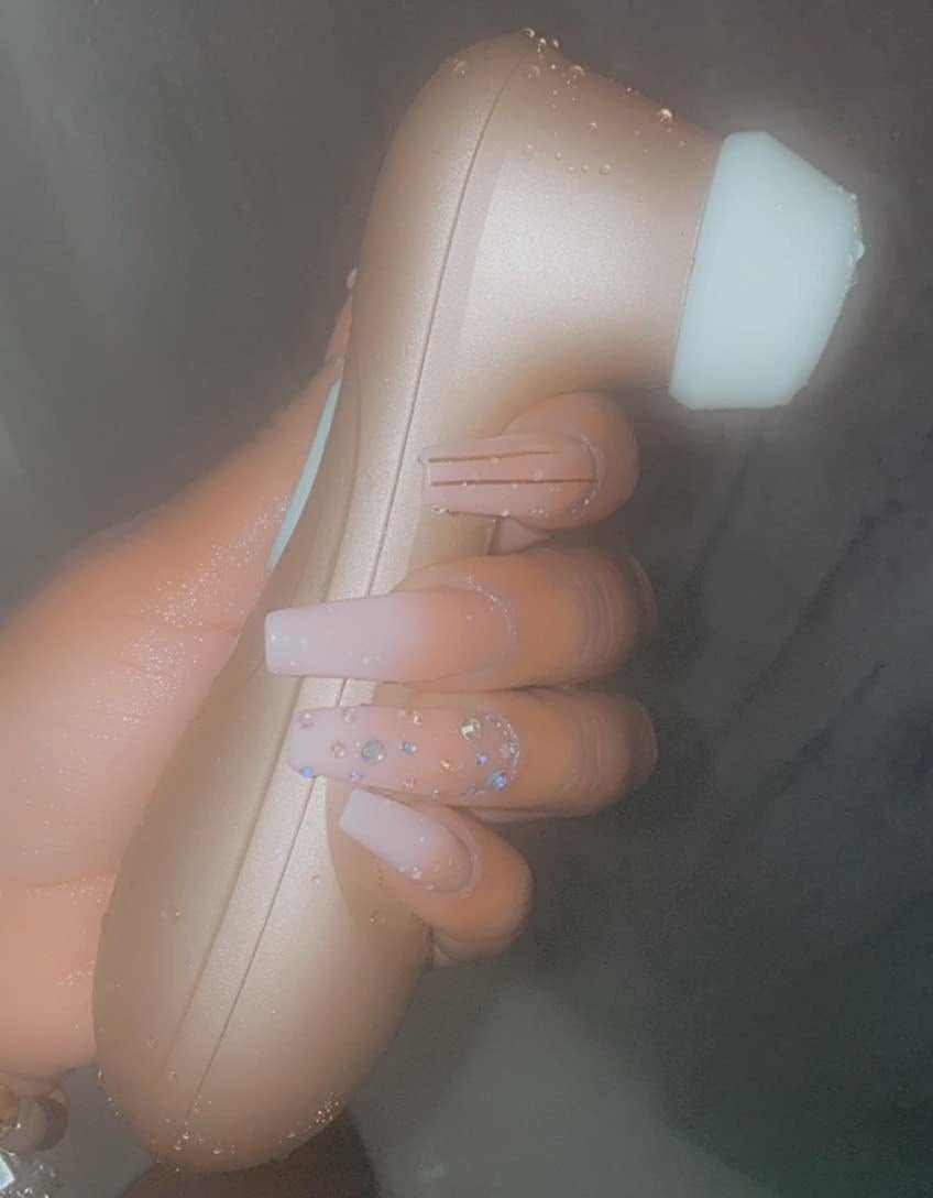 Reviewer holding rose gold suction vibrator
