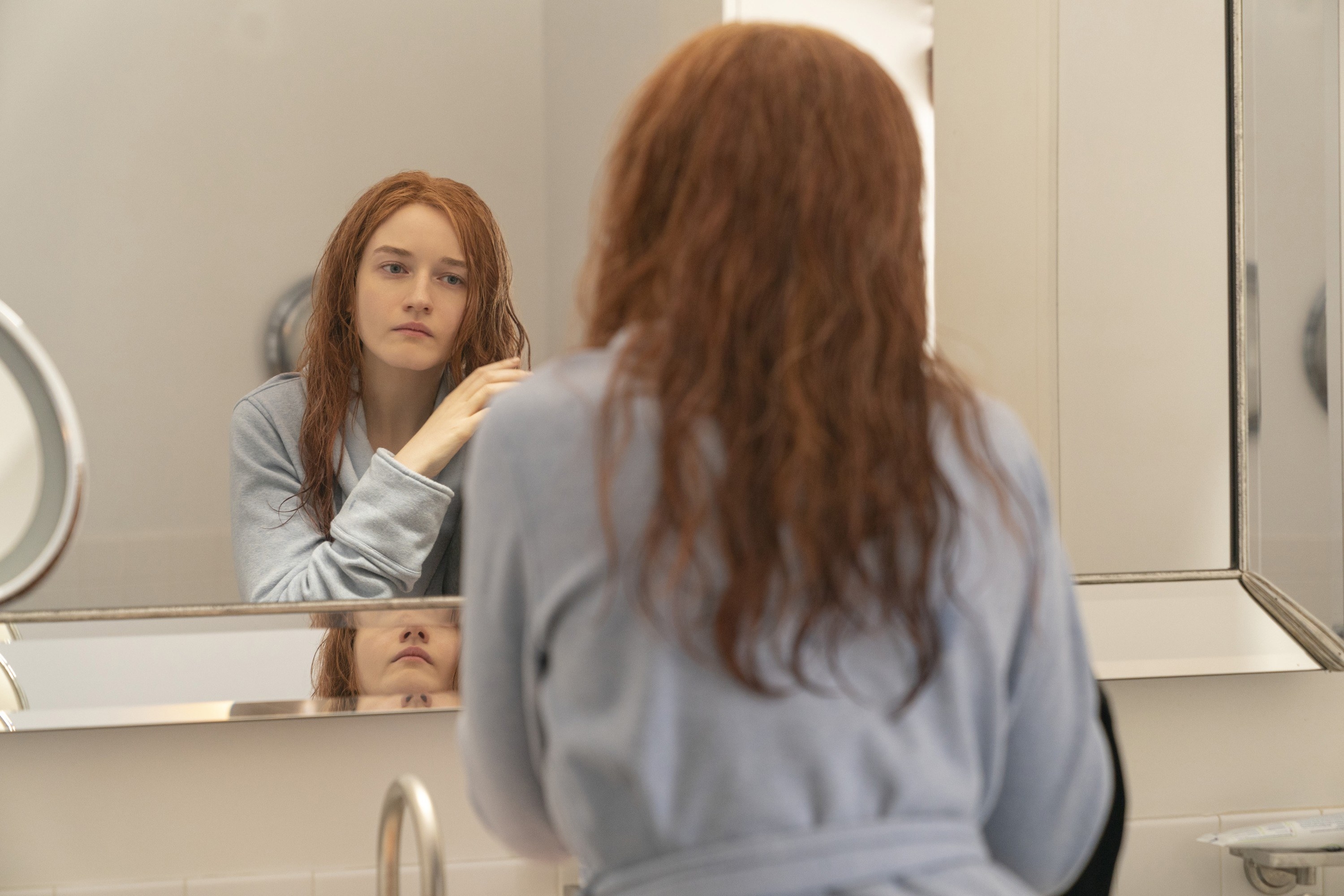 Anna fixes her wet hair in the mirror