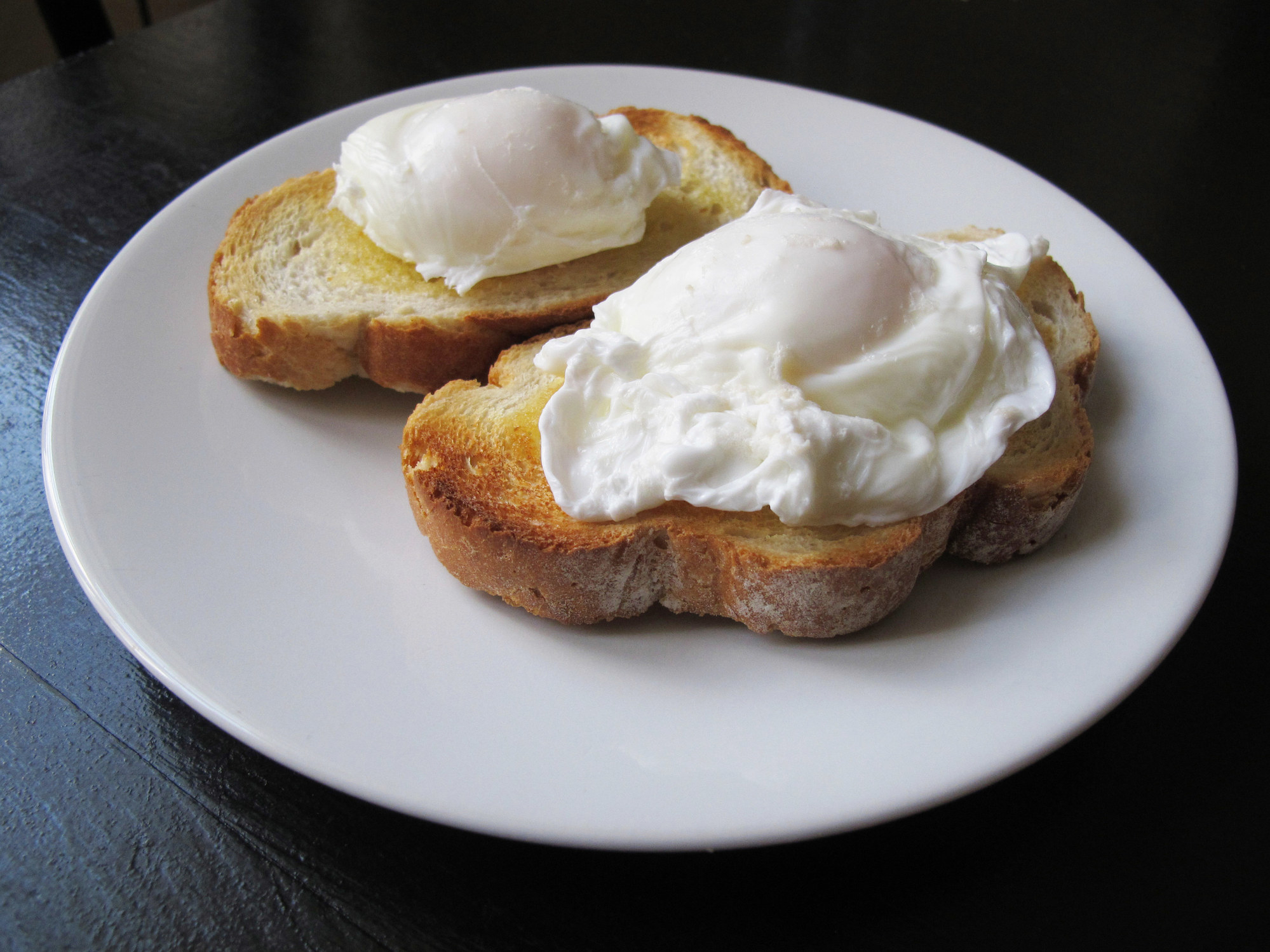Two poached eggs on toasted white rustic bread.