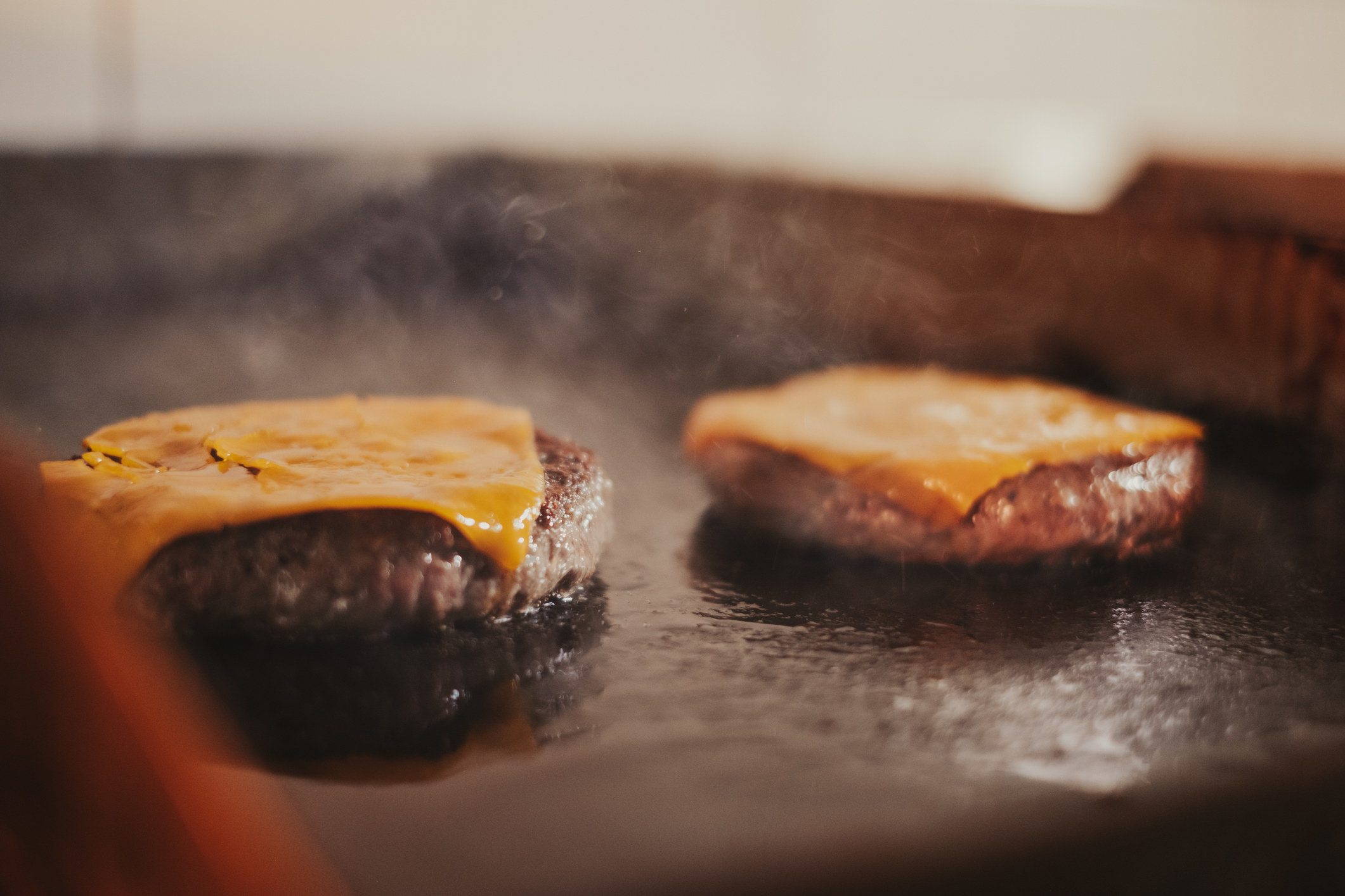 Two cheeseburgers frying on the grill.