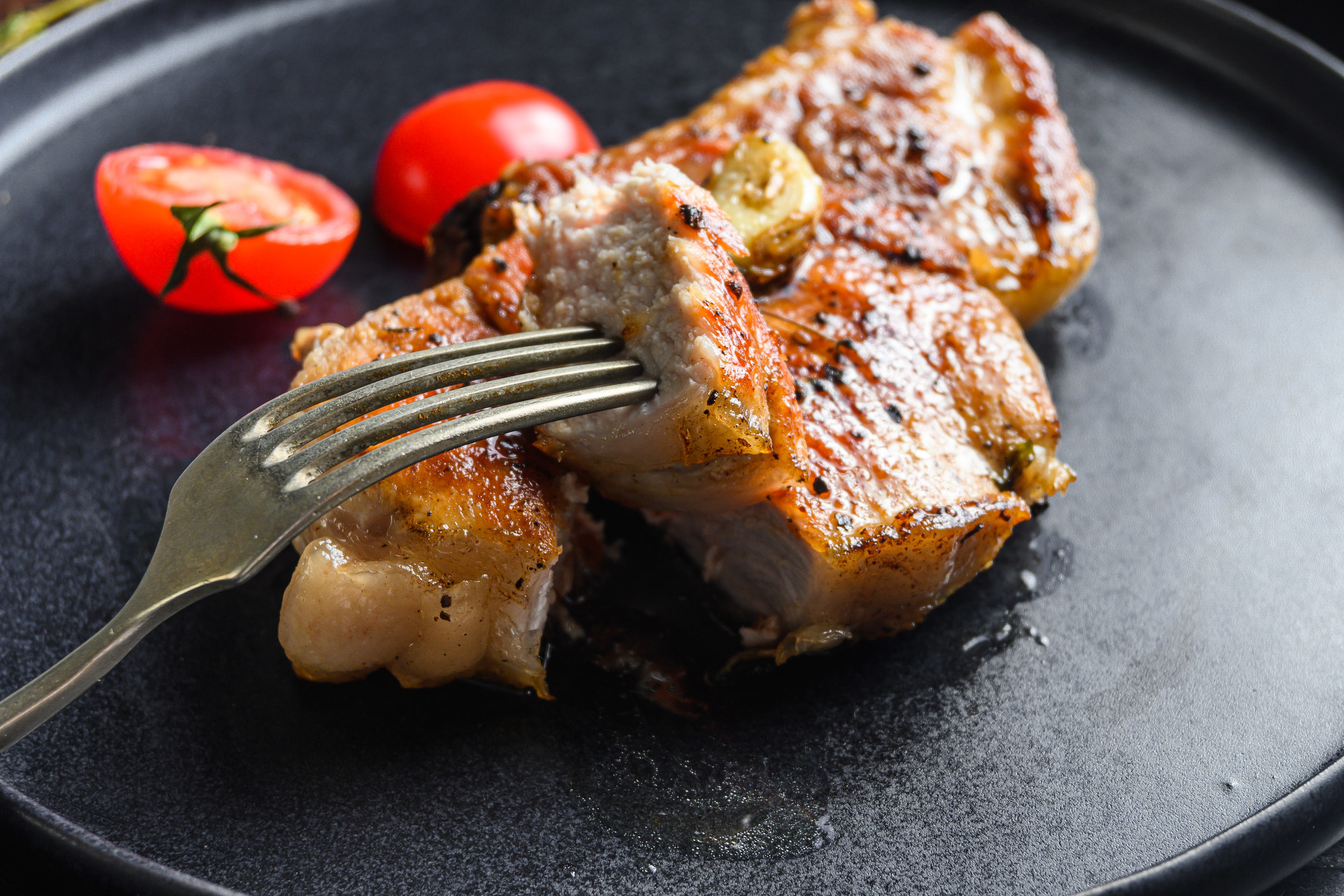 Dish of grilled pork chop with tomatoes.