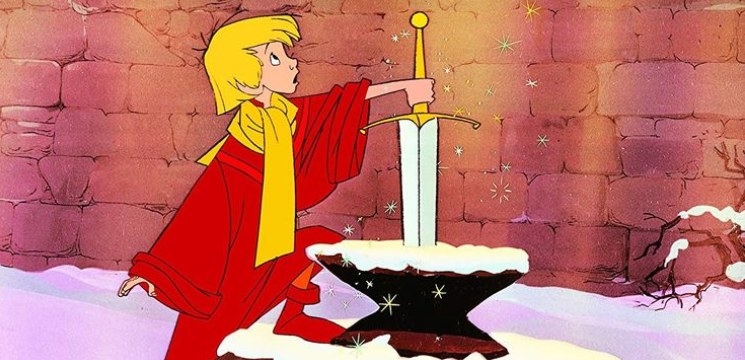 Arthur stands with one hand on the sword in cased in the stone