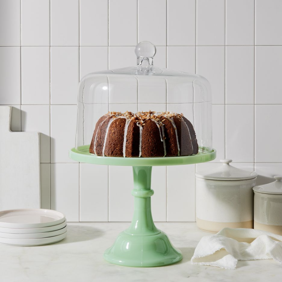 the green cake stand holding a cake that's covered with a glass dome