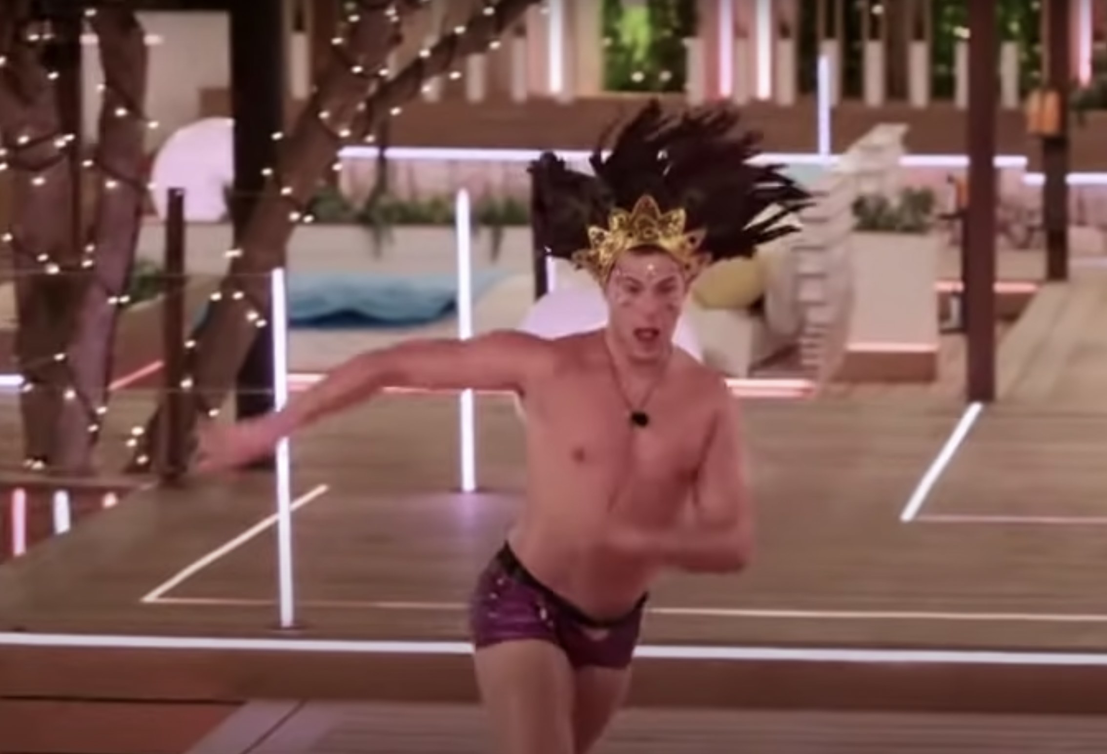Curtis wearing short shorts and a large headpiece and dancing in the heart rate challenge