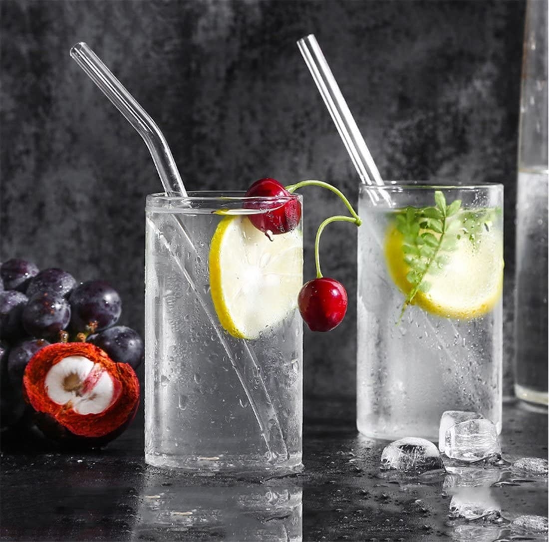 two glasses filled with drink and fresh fruit with the glass straws in them