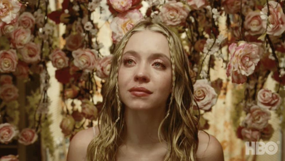Cassie crying in front of a wall of roses