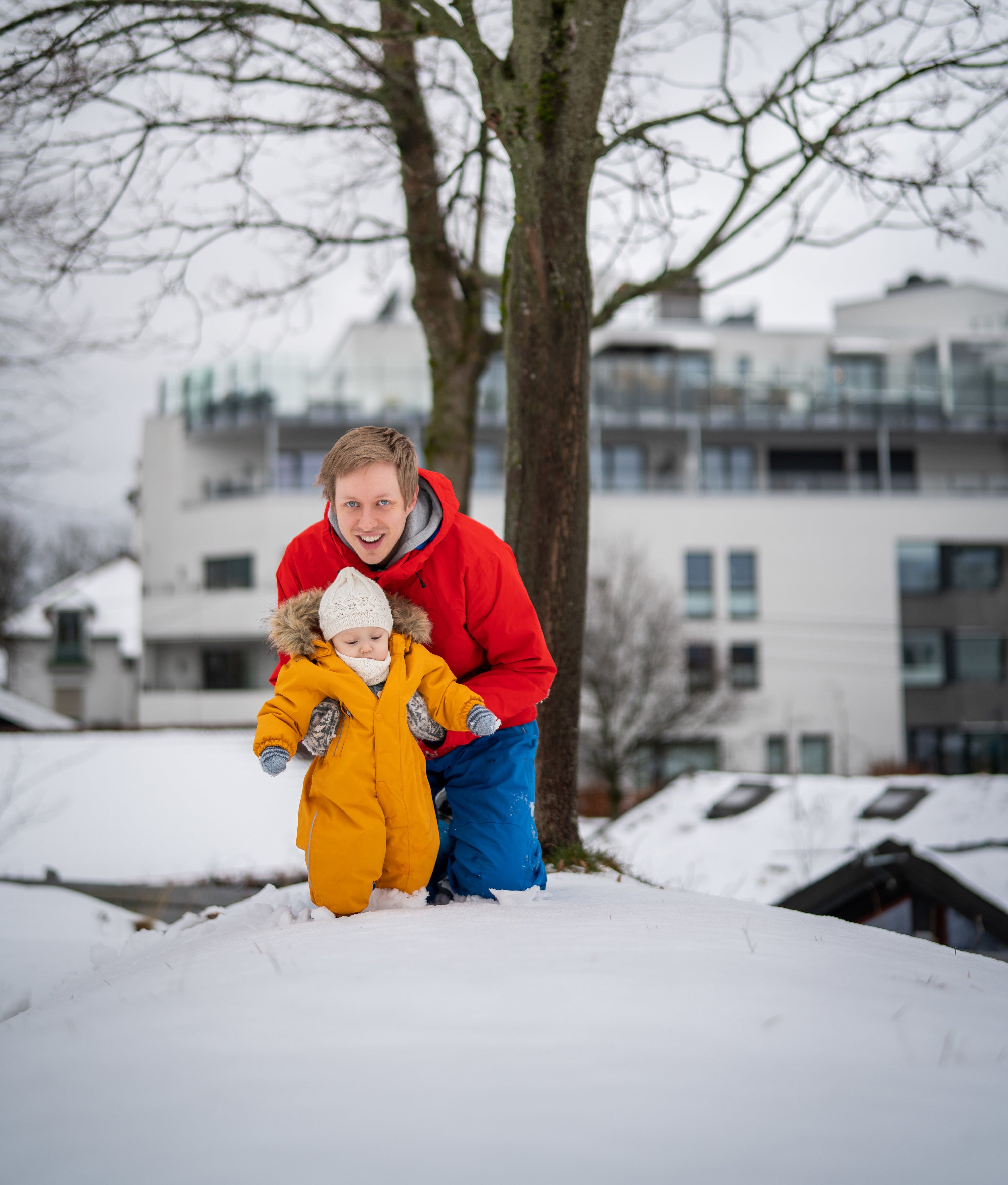 Father and son playing on a pile of snow in snow gear in Oslo