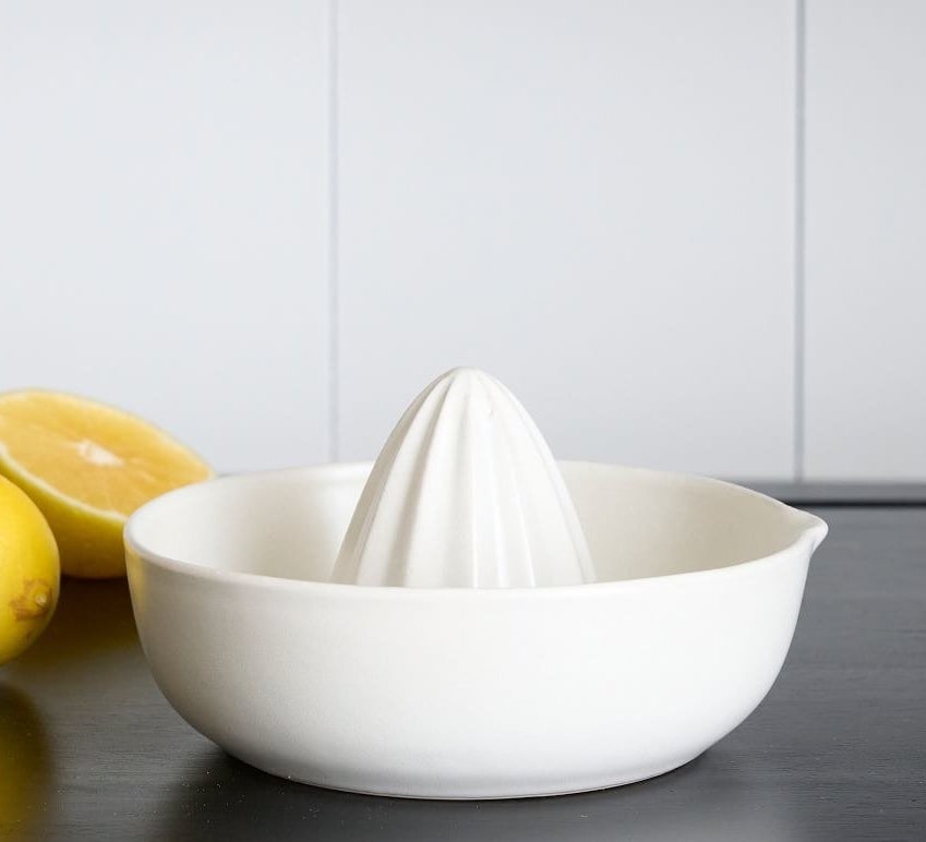 the white juicer on a counter next to some lemons