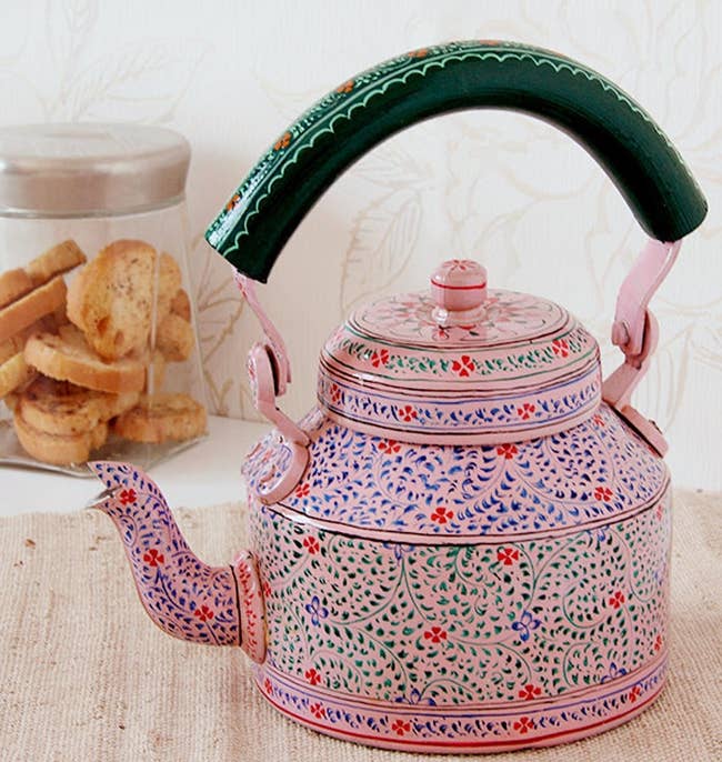 the pink painted teapot next to a jar of cookies