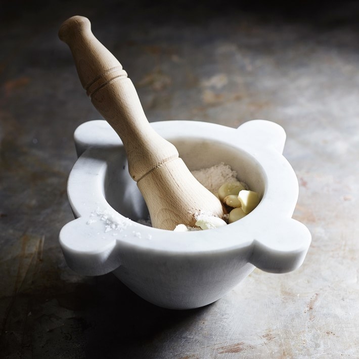 the marble mortar and pestle with garlic and salt inside of it