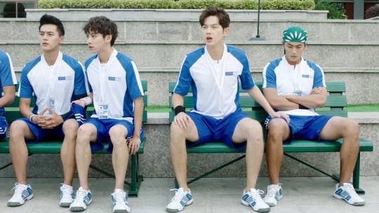 Five young men sitting in their sports uniforms on benches