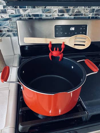 reviewer photo of the red crab attached to a pot holding a spoon