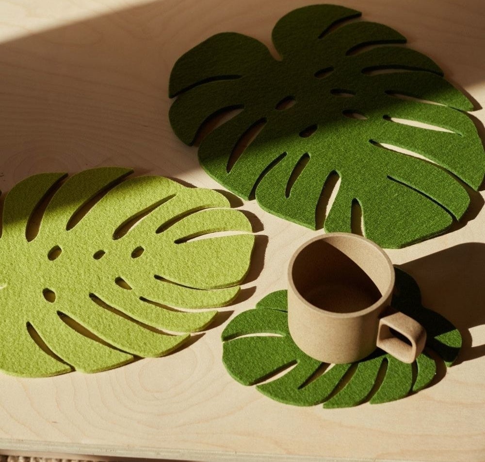 three green leaf trivets on a table, one with a mug resting on it