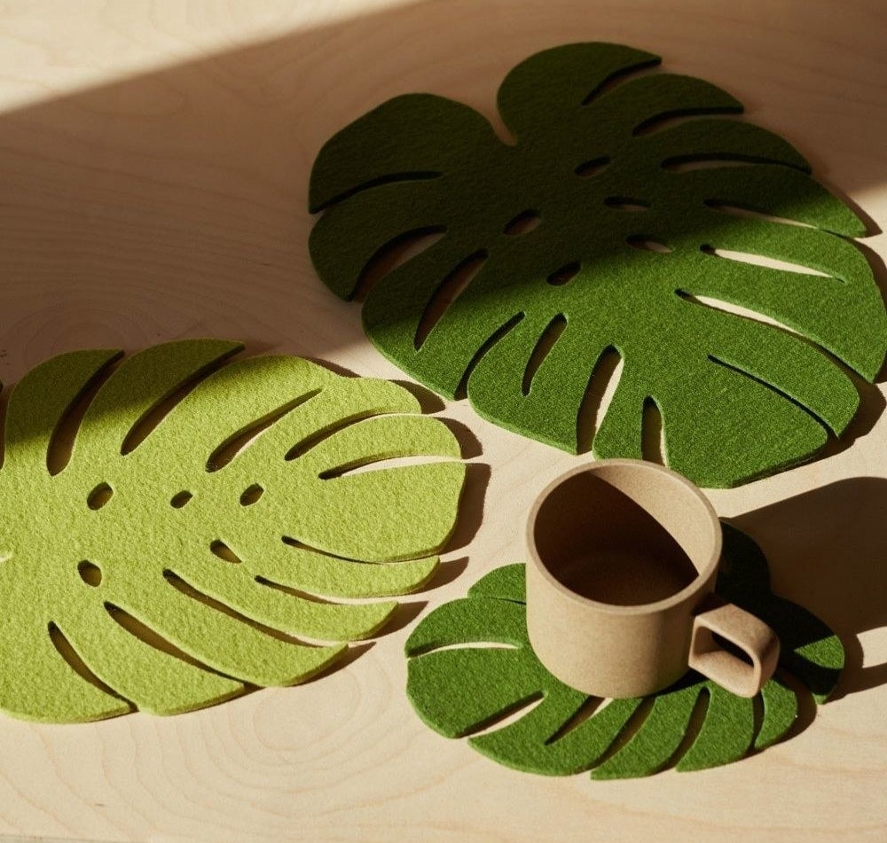 three green leaf trivets on a table, one with a mug resting on it