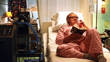 Gene Hackman as Royal Tenebaum laying in a hospital bed reading and drinking