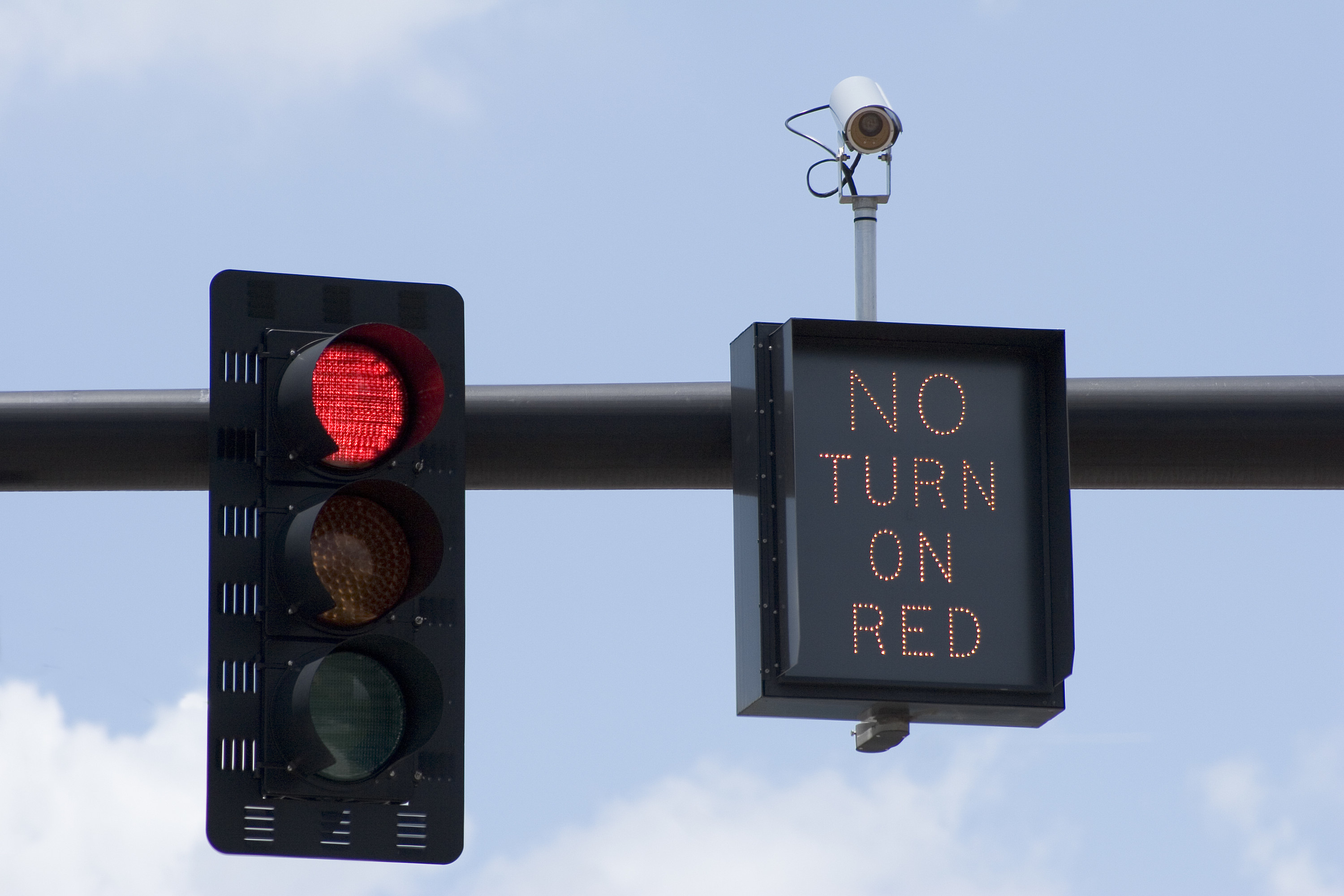 A stock image of a stop light on red, with a sign beside it that reads &quot;No turn on red&quot;