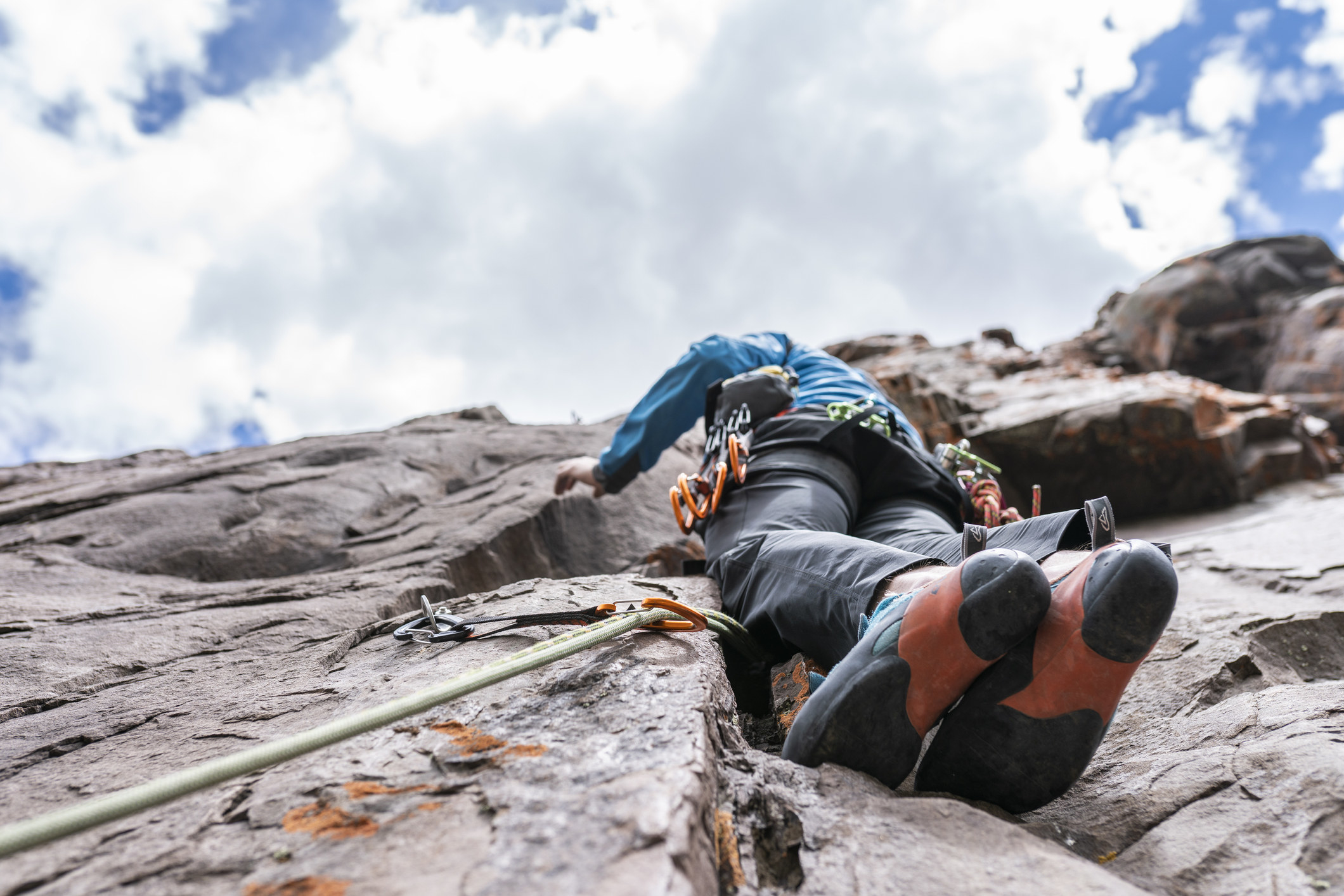 A stock image of a person climbing up the face of a rock