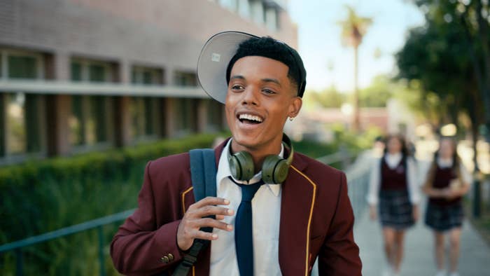 Jabari Banks as Will Smith in Bel-Air wears a school uniform with a baseball cap sideways and headphones