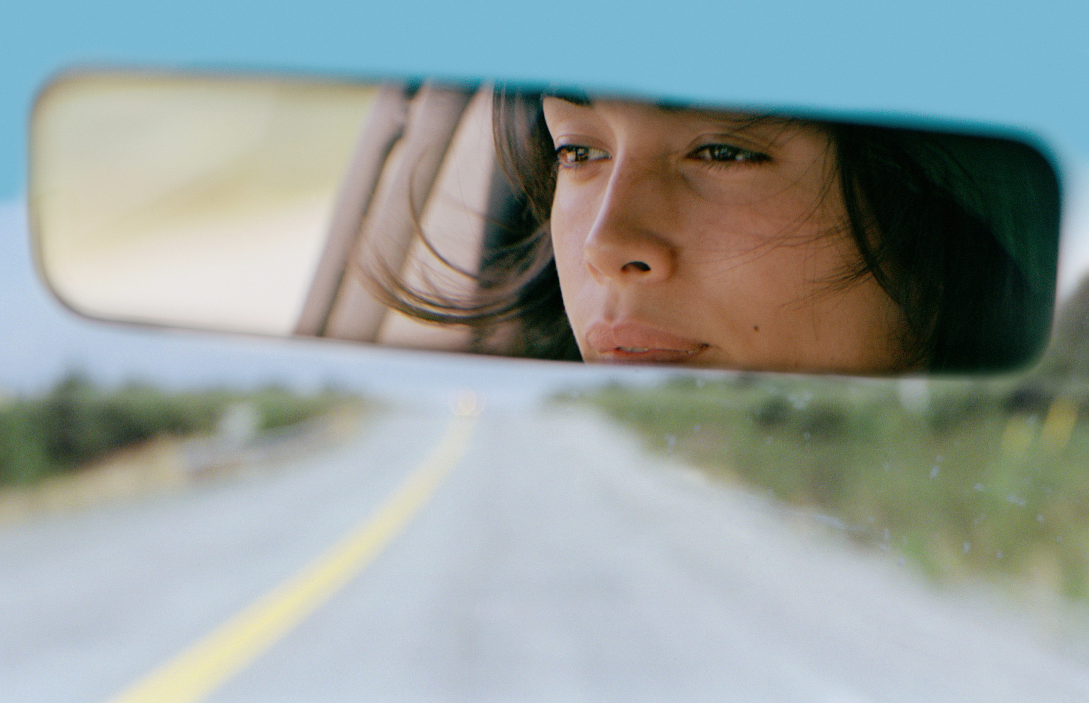 Woman driving car reflected in rear view mirror