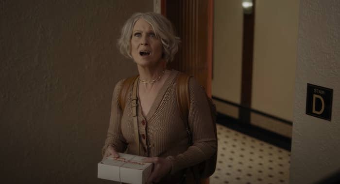 Miranda standing in a hallway while holding a small box
