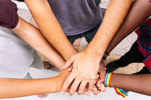 Hands of a group of people of different ethnicities with an LGBT flag bracelet