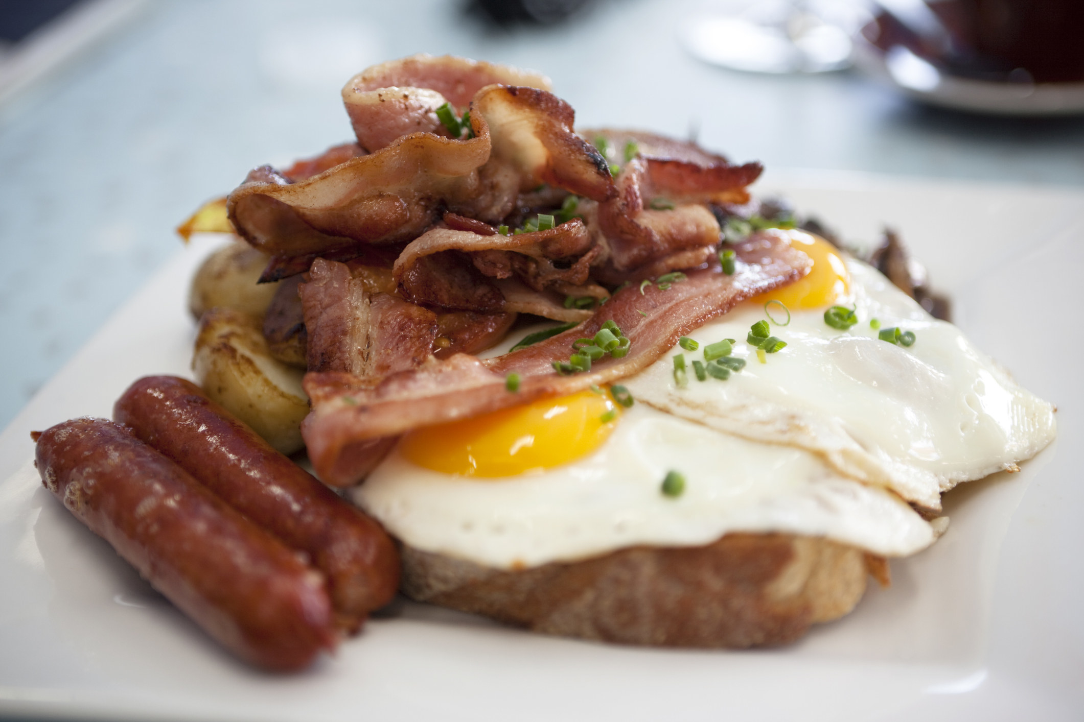 A plate of traditional bacon, fried eggs, sausages and potatoes.