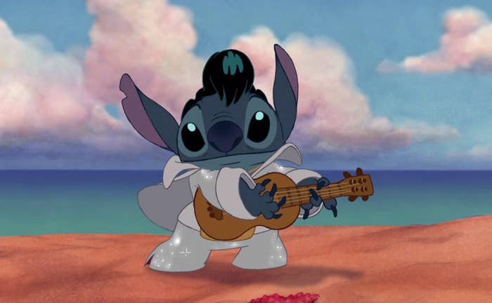 Stitch the alien dressed in a sparkly suit as he holds a small guitar