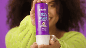 A gif of a person holding the bottle and squeezing the product into their hand