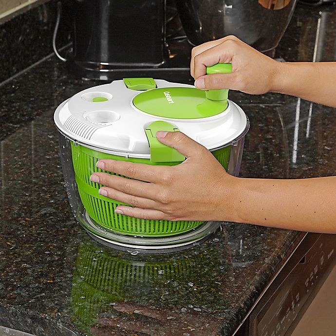 a person using the green and white salad spinner