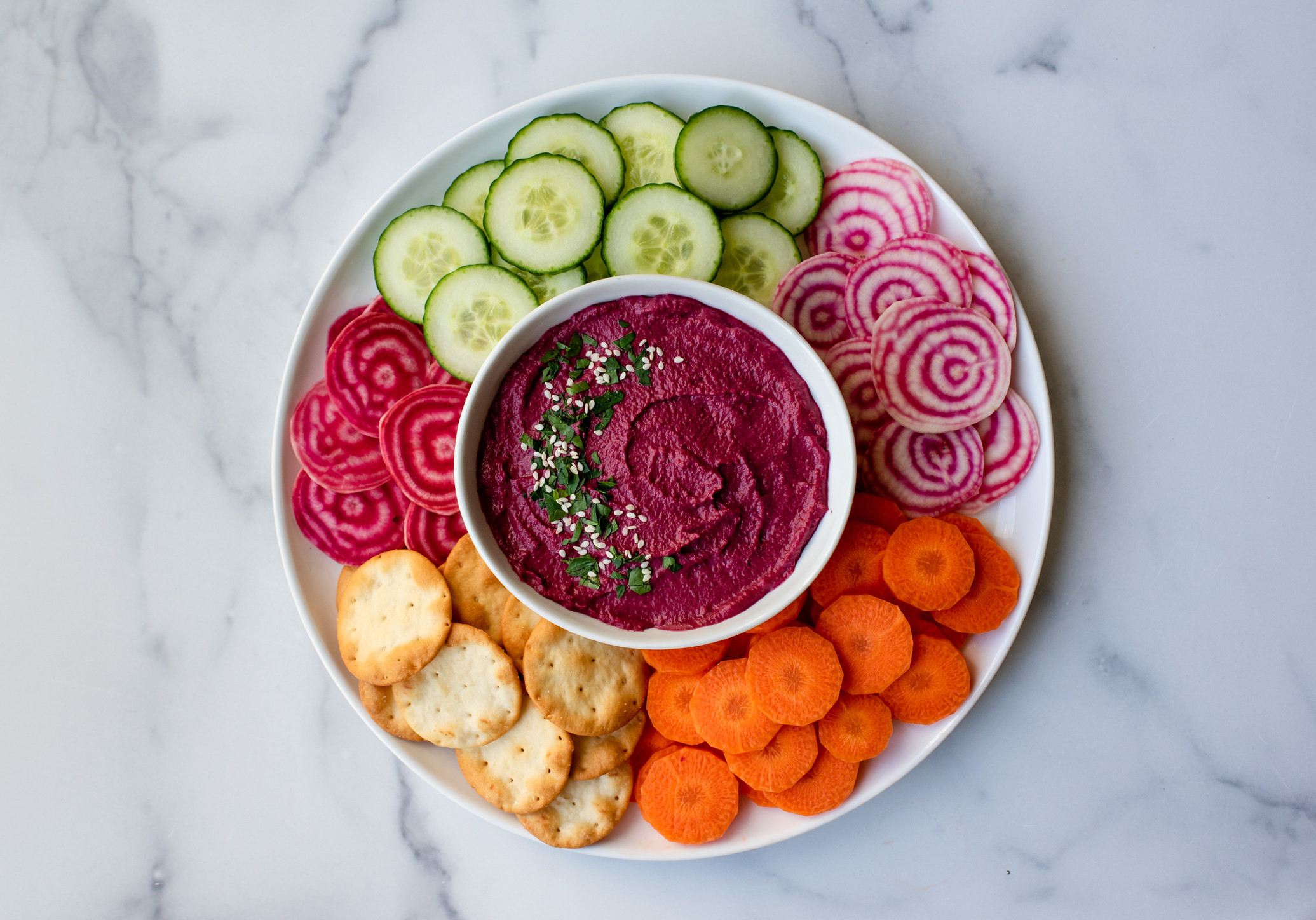 Bowl of beet hummus, vegetables and crackers.