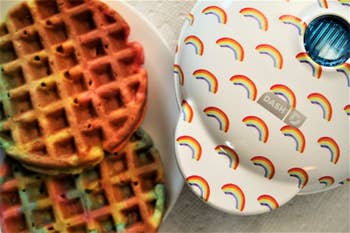 reviewer photo of the rainbow waffle maker next to a plate of rainbow waffles