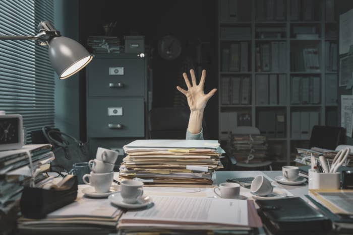 Person drowning in paperwork at their desk