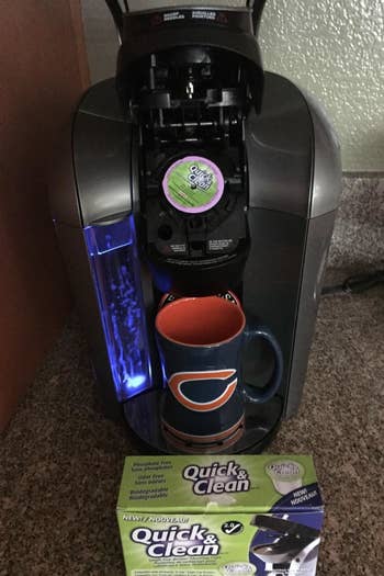 a reviewer photo of the open Keurig with a cleaning cup inserted